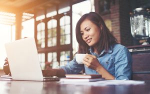 Woman with coffee in front of laptop