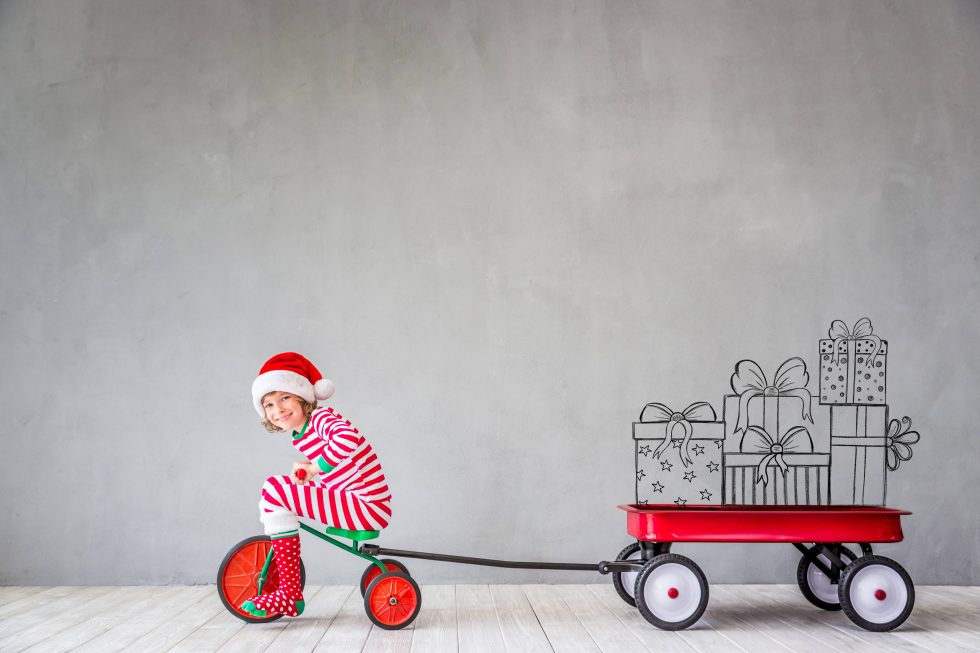 Adorable child pulling holiday presents on a wagon