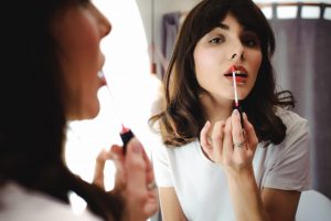 Woman Applying Lip Gloss in Mirror Beauty Coronavirus