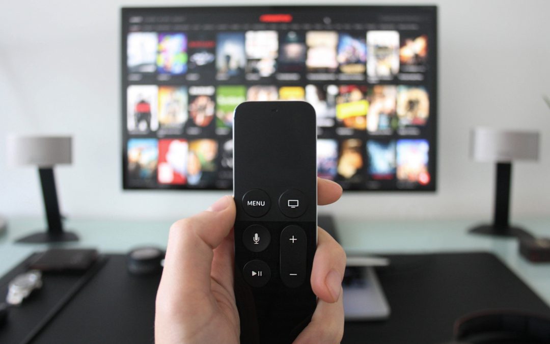 choosing a streaming show holding remote in front of options on television