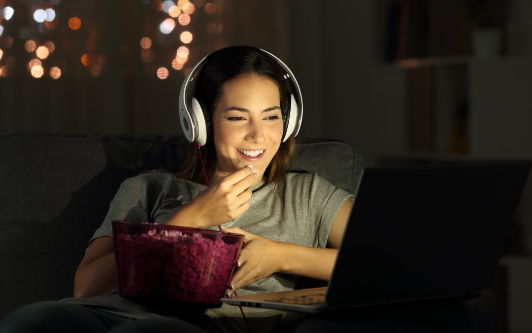 woman streaming with popcorn and headphones on laptop netflix