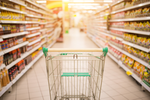 Supermarket,Aisle,With,Empty,Red,Shopping,Cart,With,Customer,Defocus