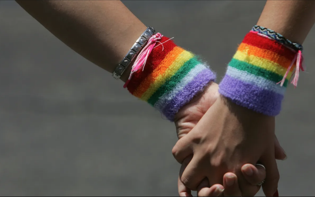 holding hands wearing rainbow bracelets for pride month LGBTQ+