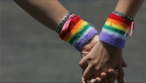 holding hands wearing rainbow bracelets for pride month LGBTQ+