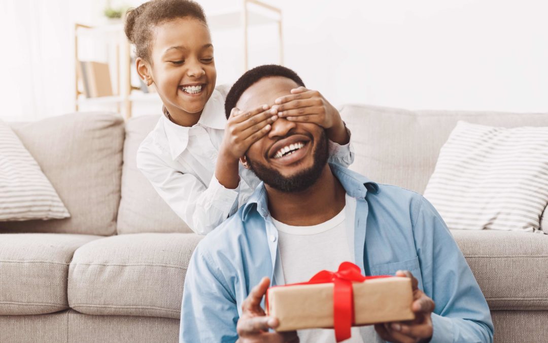 Father and child on Father's Day with gift. Father's day advertising and gift trends 2022. Happy daughter congratulating dad and giving present at home