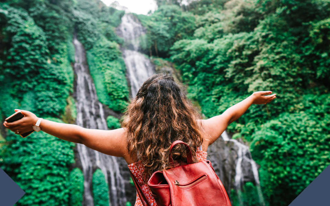 woman hands wide in front of waterfall wearing backpack for travel trends advertising trends travel and pride