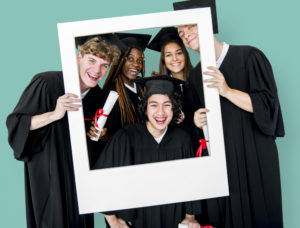 Diverse,Students,Wearing,Cap,And,Gown,Holding,Photo,Frame,Studio